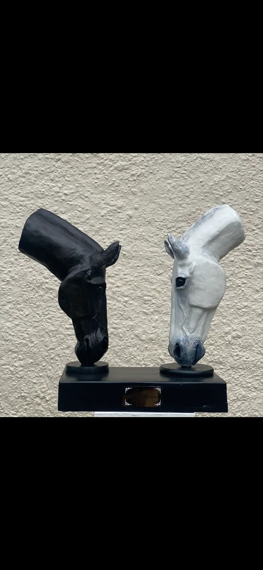Hand-sculpted pair of horse-head sculptures — one black, one white — facing each other on a black plinth, Soul Attraction