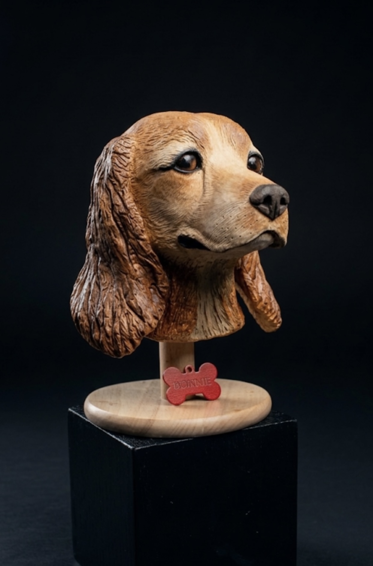 Hand-sculpted clay portrait of Bonnie the cocker spaniel on a wooden plinth with name tag