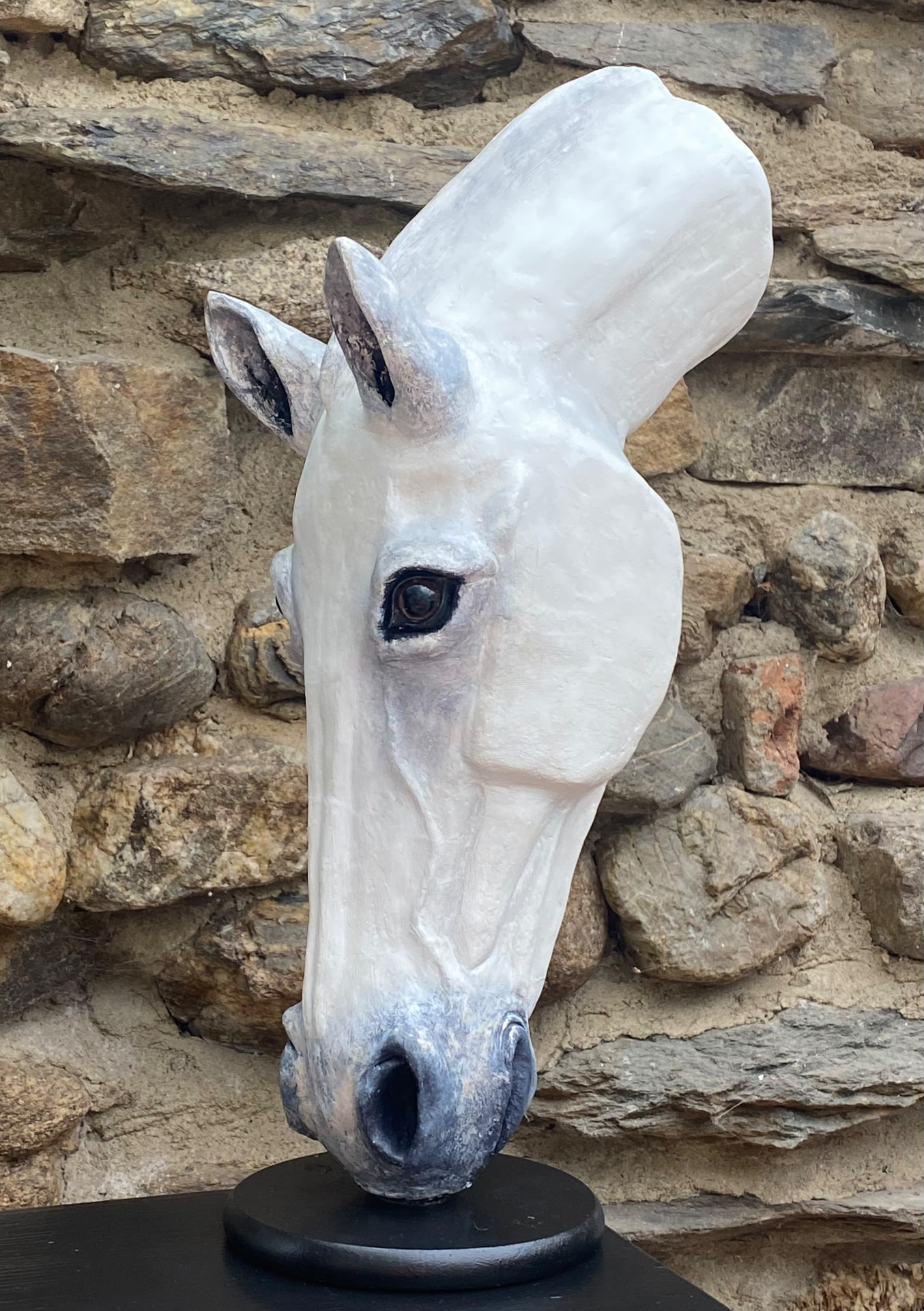 Hand-sculpted white horse-head sculpture of Soul Dawn, profile view on a black plinth against a stone wall